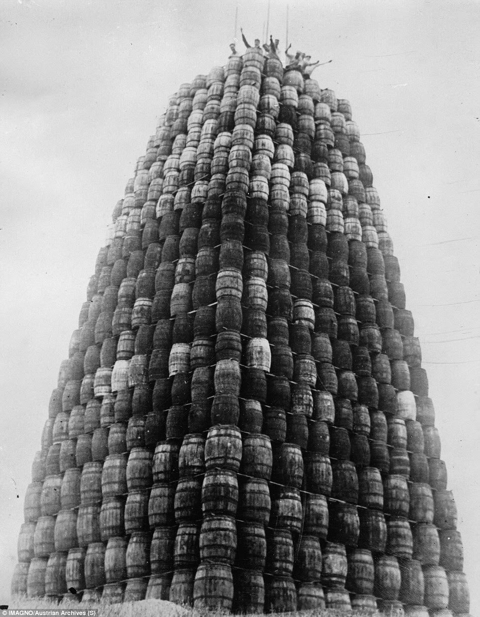 Workers wave from the top of a tower of confiscated alcohol in 1929
