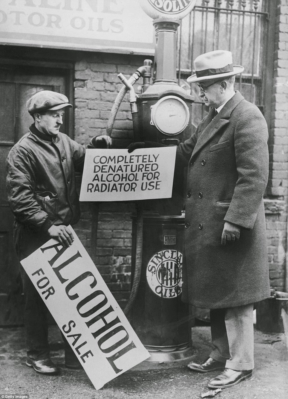 A New Jersey prohibition director, right, gives a Newark garage owner an approved sign for selling alcohol that can be used in car radiators in 1927