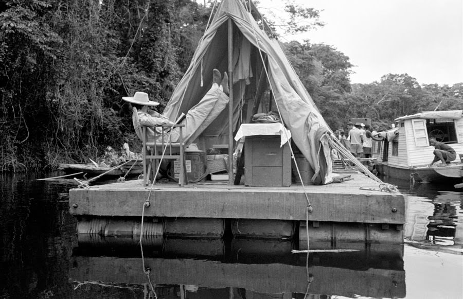 Katharine Hepburn, her face concealed by her massive hat, puts up her feet.