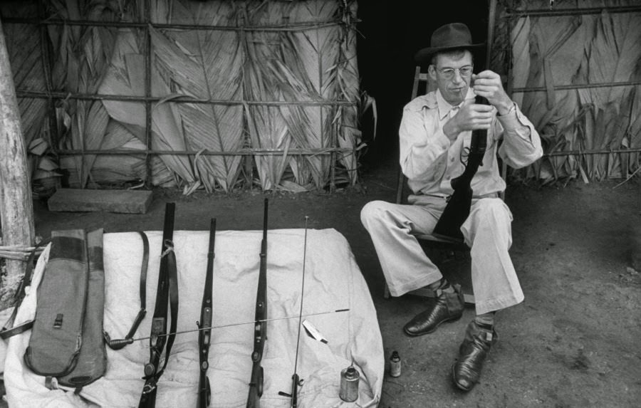 Director John Huston examines one of his rifles during filming of The African Queen, 1951.