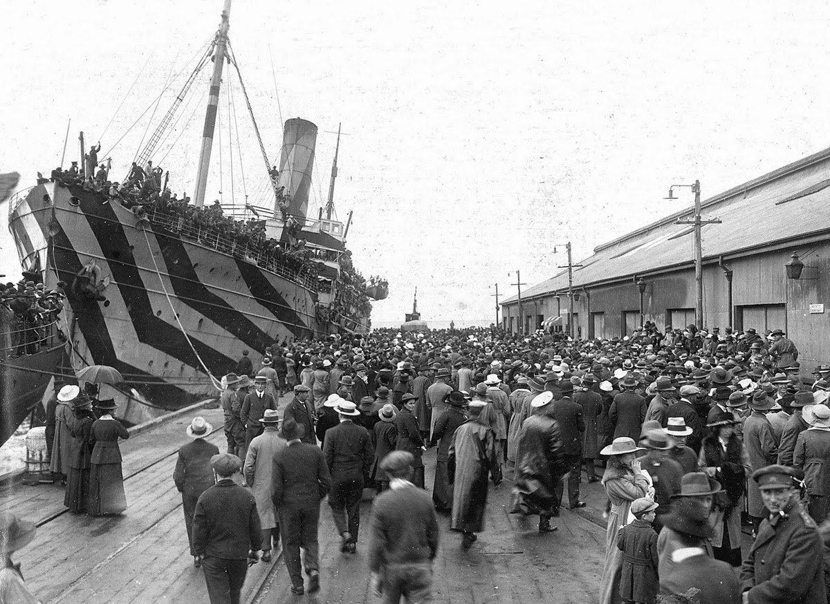Crowds on a wharf at Outer Harbour, South Australia, welcoming camouflaged troop ships bringing men home from service overseas, circa 1918.