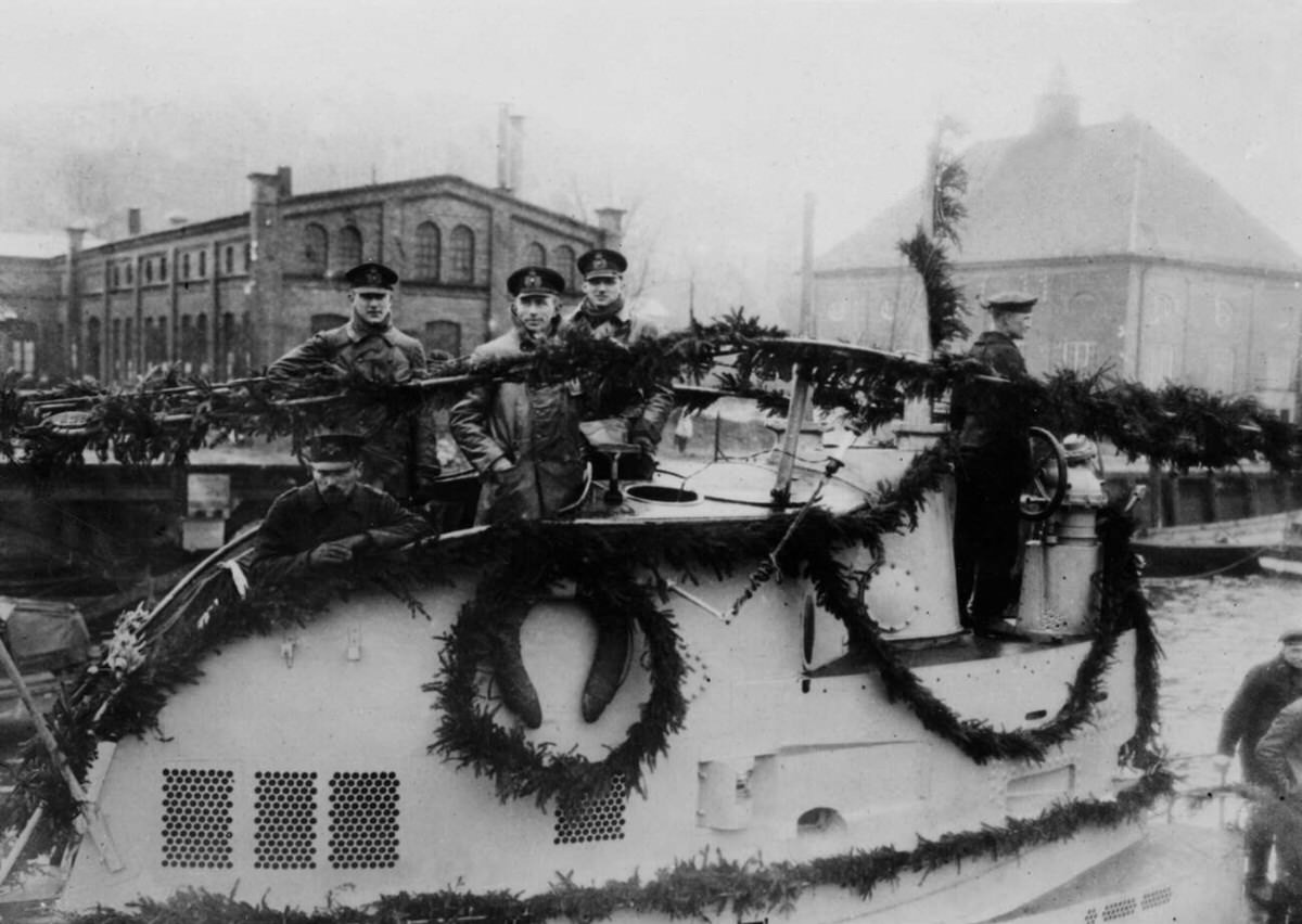 Officers on the turret of a be-garlanded submarine putting out to sea, April 1917.