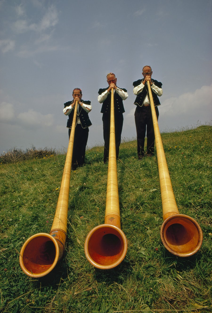 Swiss men playing 12-foot-long alpenhorns at a midsummer Alpine Festival in Switzerland, 1973