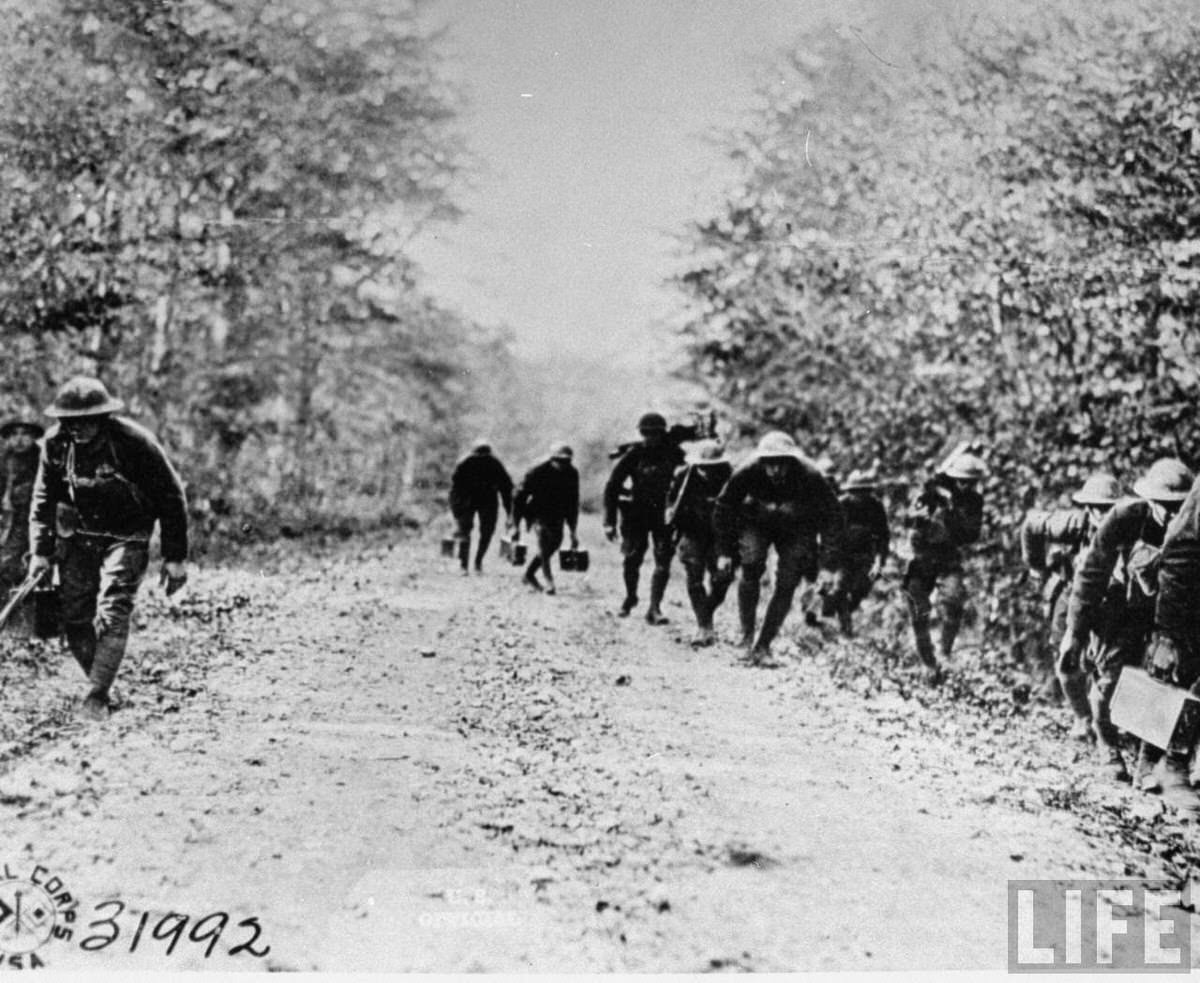 American machine gun platoon creeping along a small road near the front lines during World War I.