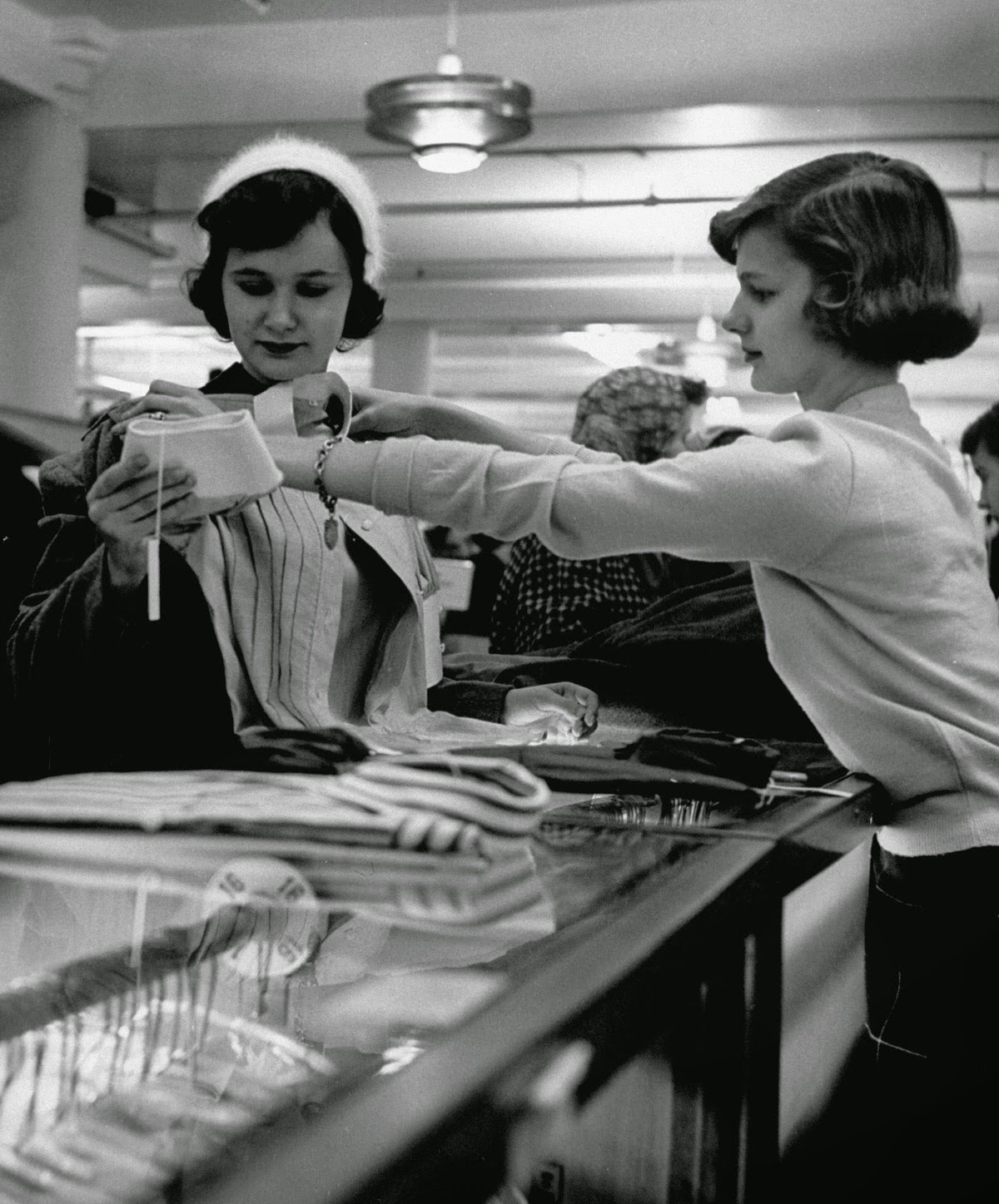 Teenage salesgirl showing a blouse to a customer, 1954