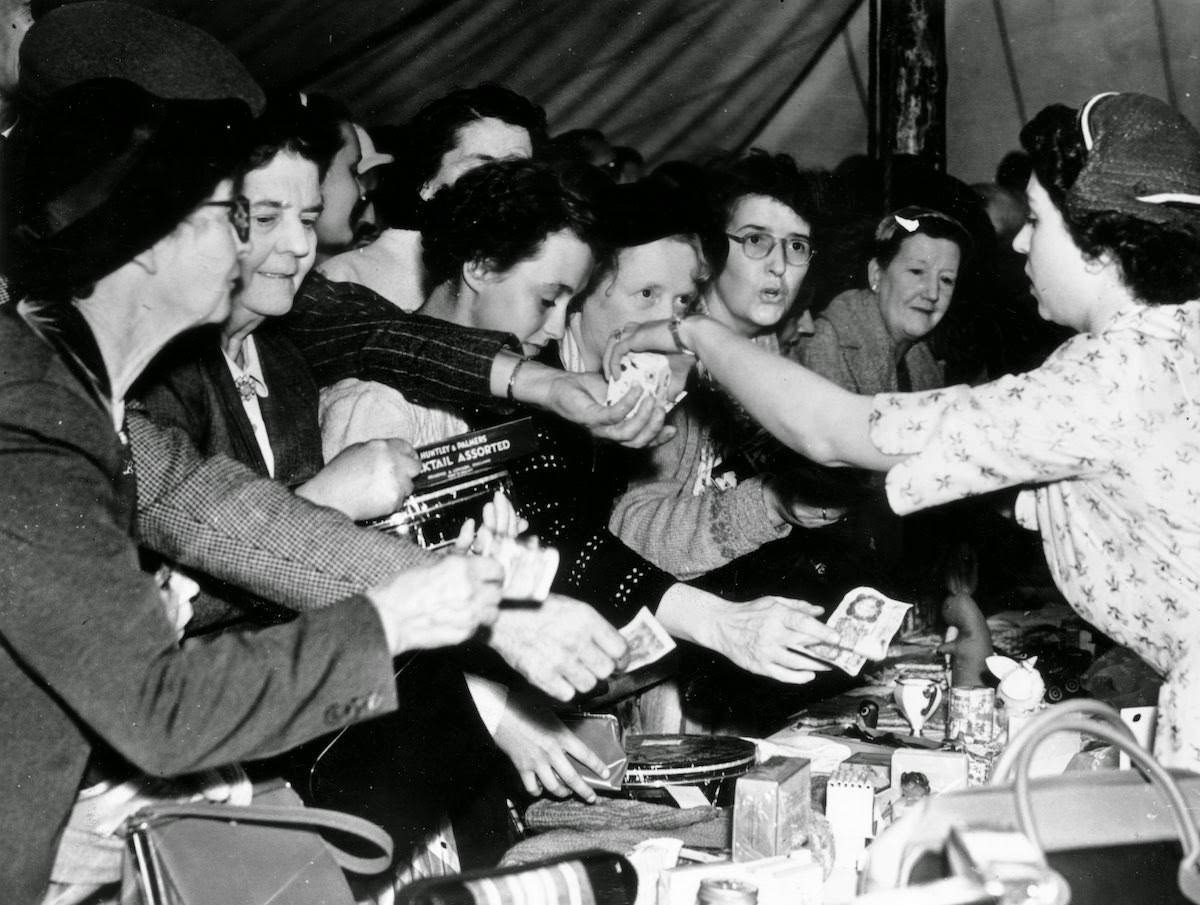 Queen Elizabeth II selling an item during a sale at Abergeldie Castle in Scotland to raise funds for Crathie Church, 1955