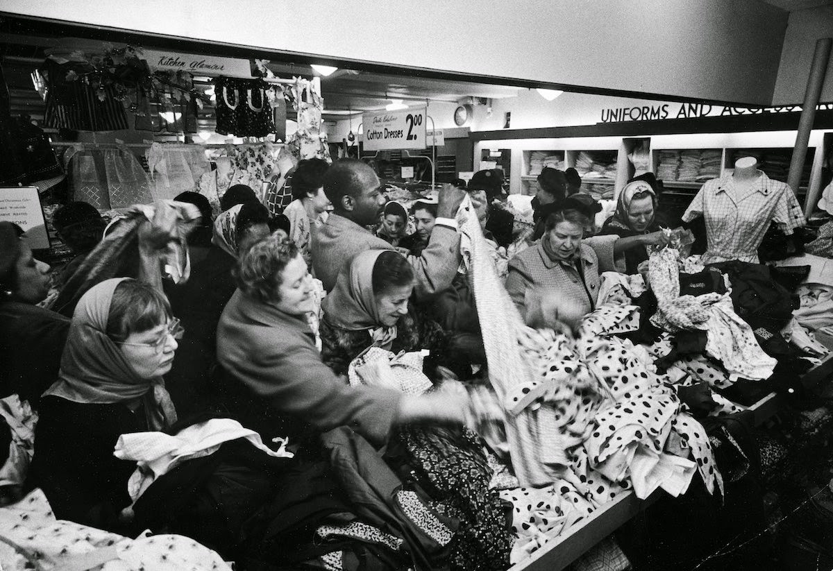 Women grabbing at dresses during a Christmastime bargain sale, 1955