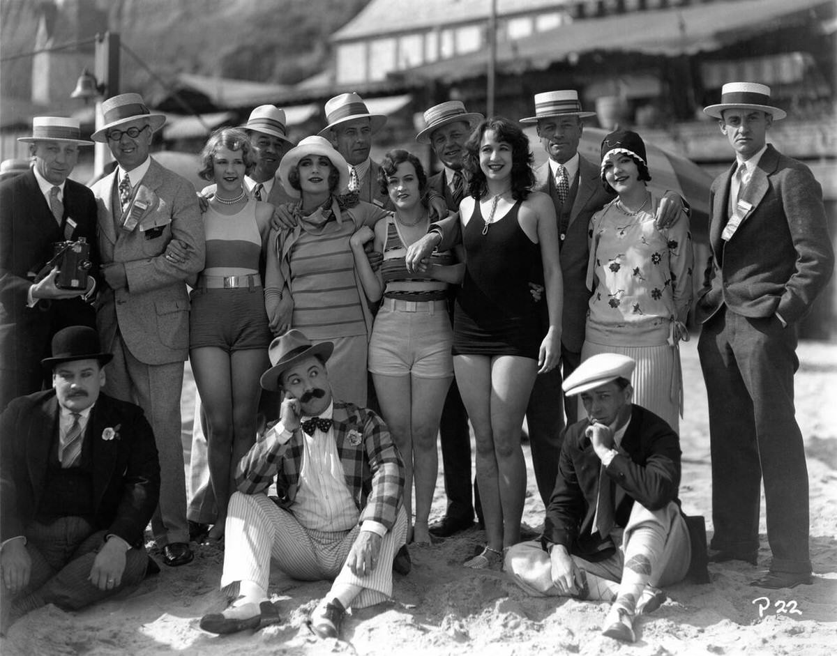 Mack Sennett comedians and Bathing Beauties posing with movie theater exhibitors on the beach, 1928