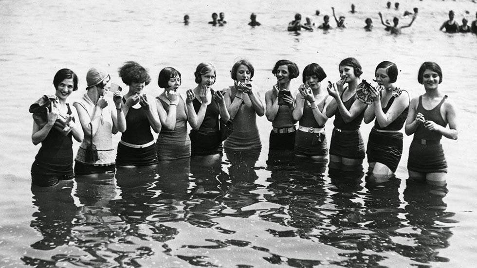 Girls of The Merry Whirl applying make-up on Manhattan Beach, New York, during a water carnival, 1924