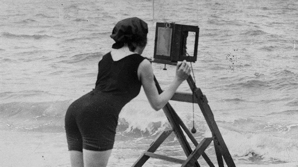 Professional photographer using a ladder to steady her camera on the beach at Ostend, 1924