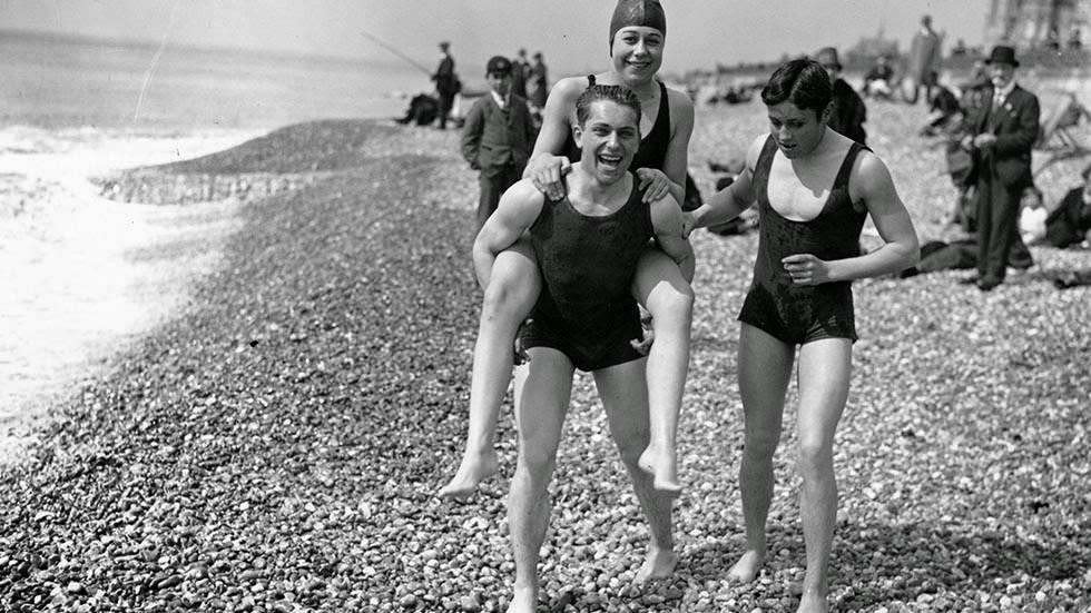 Male bather carrying a female friend on the beach at Brighton, 1927