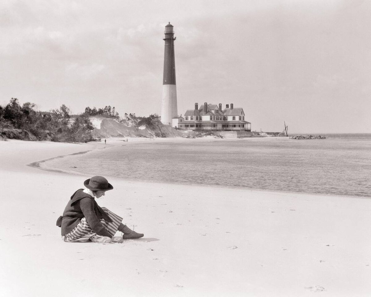 Young woman sitting alone on the sand near Barnegat Lighthouse on Long Beach Island, New Jersey, 1920