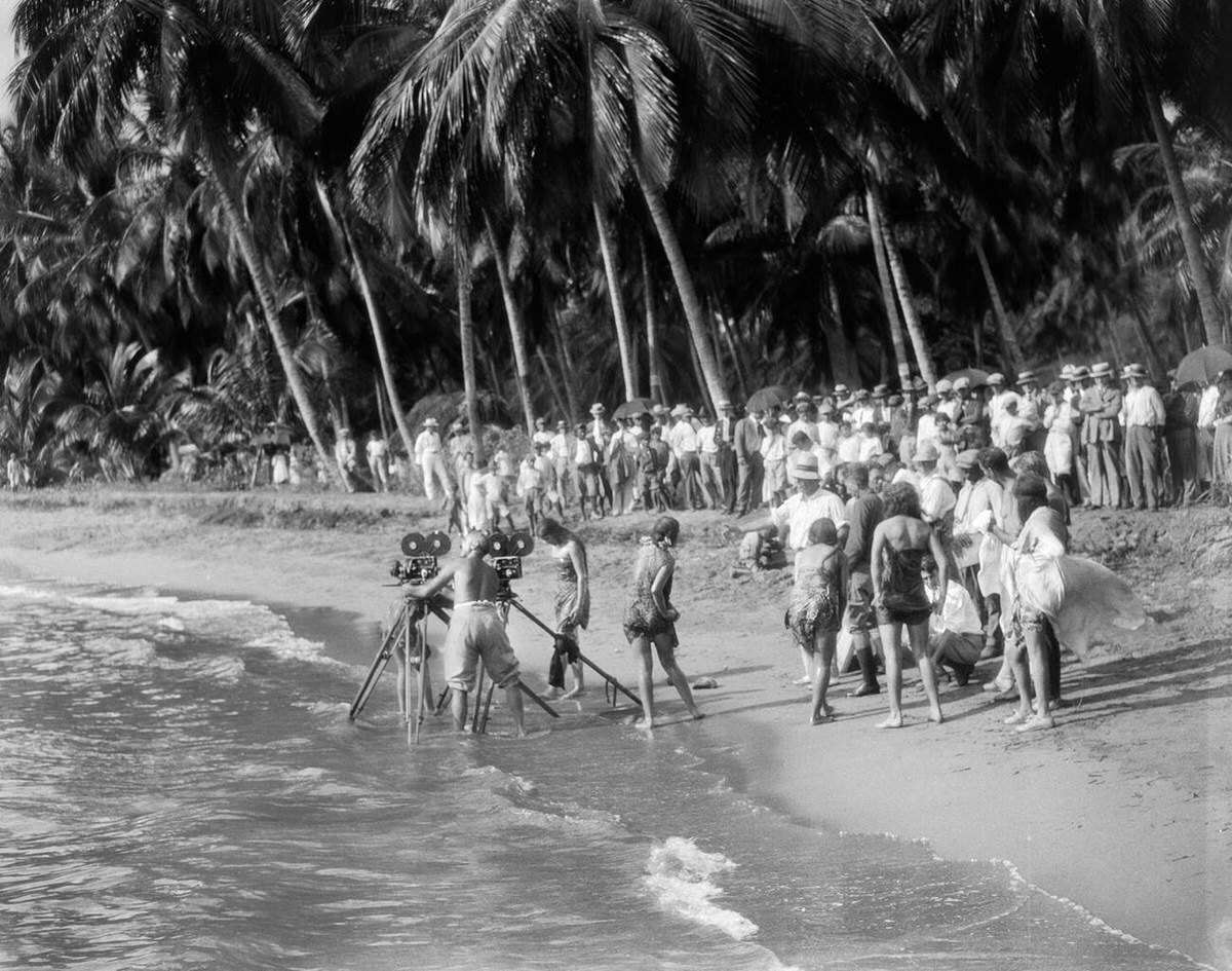 Movie crew with cameras on tripods in the surf on a tropical beach, 1920