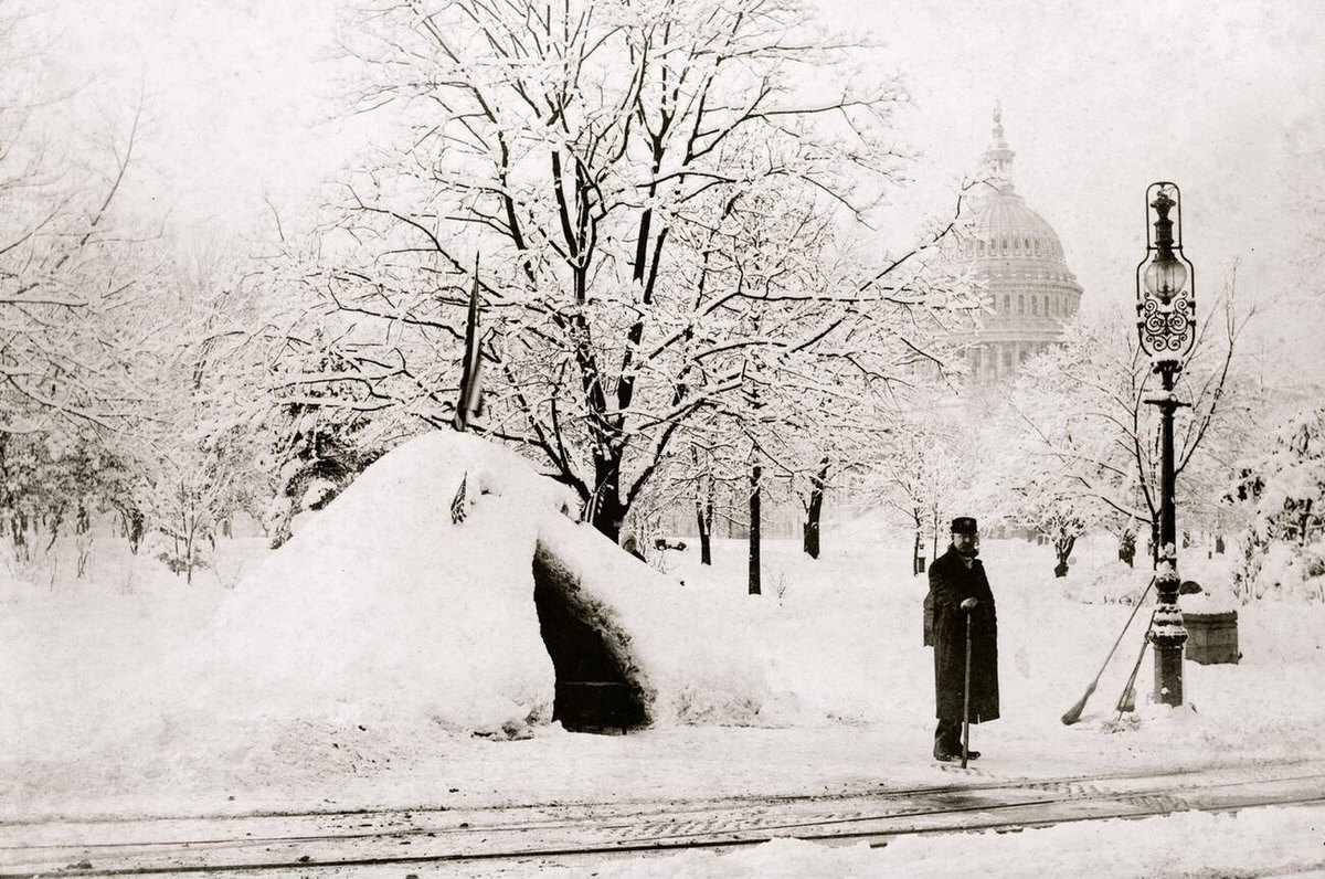 Man standing by a snow hut after the blizzard of 1888 with the U.S. Capitol in the background, Washington, D.C., 1888