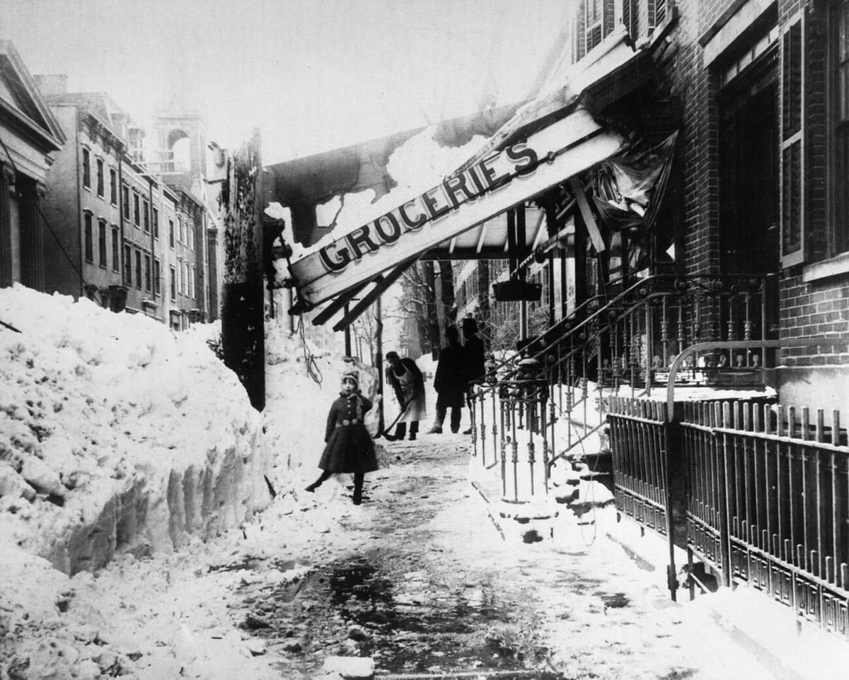 Man shoveling snow beneath a collapsed grocery store awning in New York City after the blizzard of March, 1888.