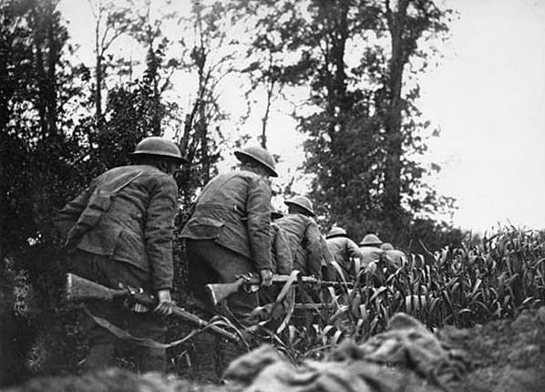 Royal Scots in No Man's Land, France, during World War I. This photograph shows a party of soldiers from the Royal Scots Regiment creeping along between a field and a hedge. The caption indicates they were advancing in 'No Man's Land', the ground between the Allied and German front line trenches.