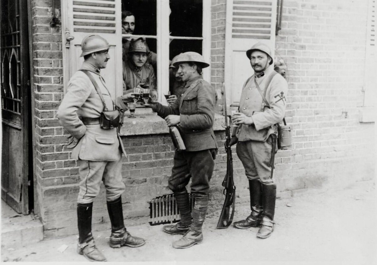 British and French soldiers having a drink at a window in France, 1914
