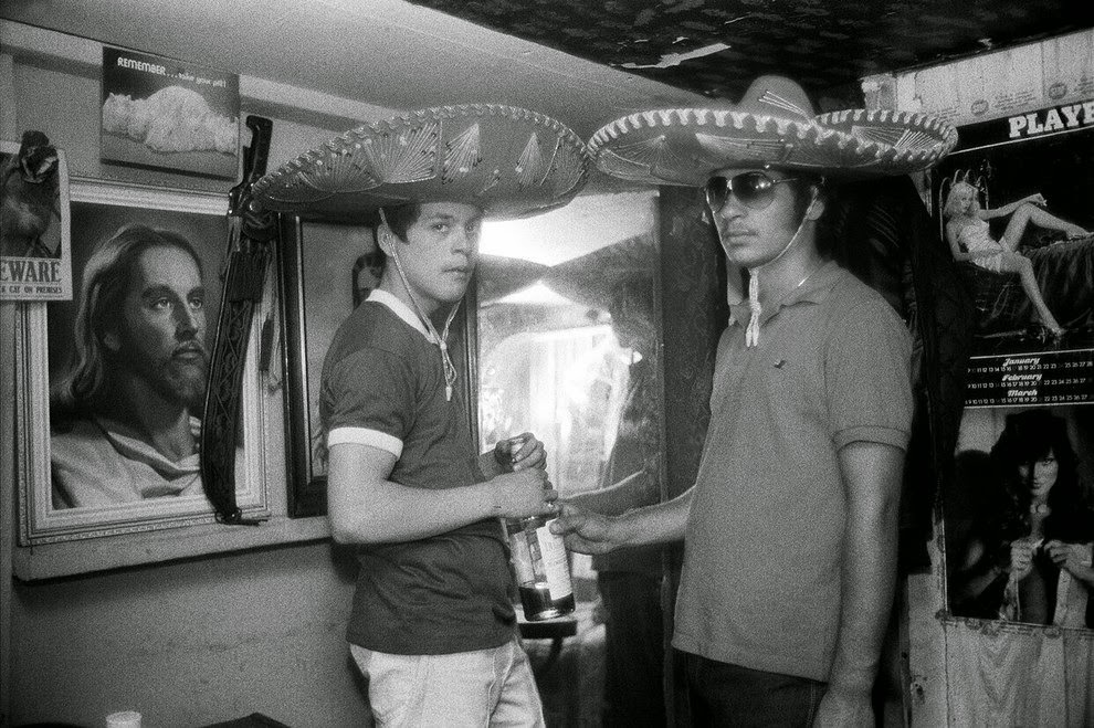 Two teenage boys wear Mexican hats as they drink inside a social club. Batgate Avenue, 1984.