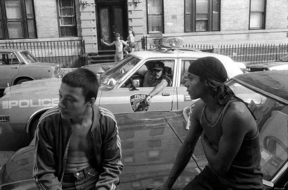 New York City police stop their car to check out two youths, who are not selling drugs, but who are hanging out on a known drug corner, 1980s.