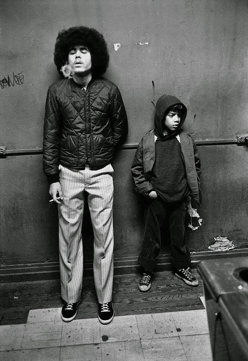 Man blows smoke rings next to elementary school age kid in pool hall, 1980.