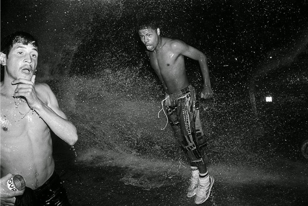 Poncho and Tony cool off in water from the pump (fire hydrant) on a hot summer night, 1980s.