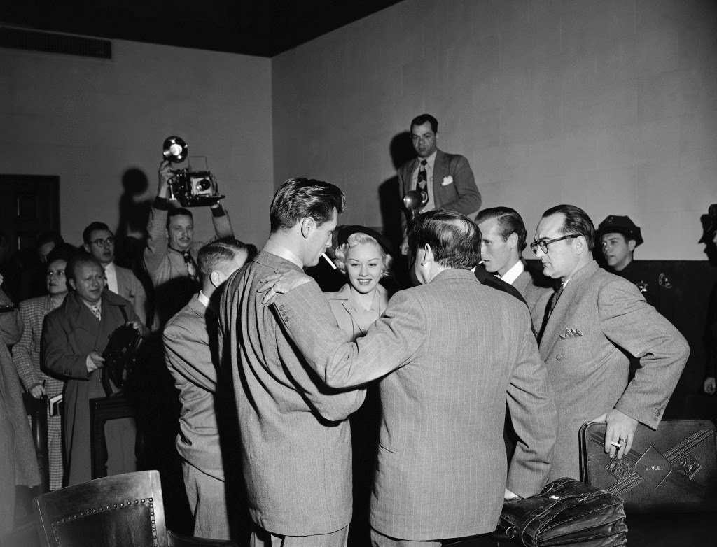 Robert Mitchum and Lila Leeds, both at left, talk with their attorneys and real estate man Robin Ford, second from right, immediately after the screen players and Ford were convicted, Jan 10, 1949 in Los Angeles.
