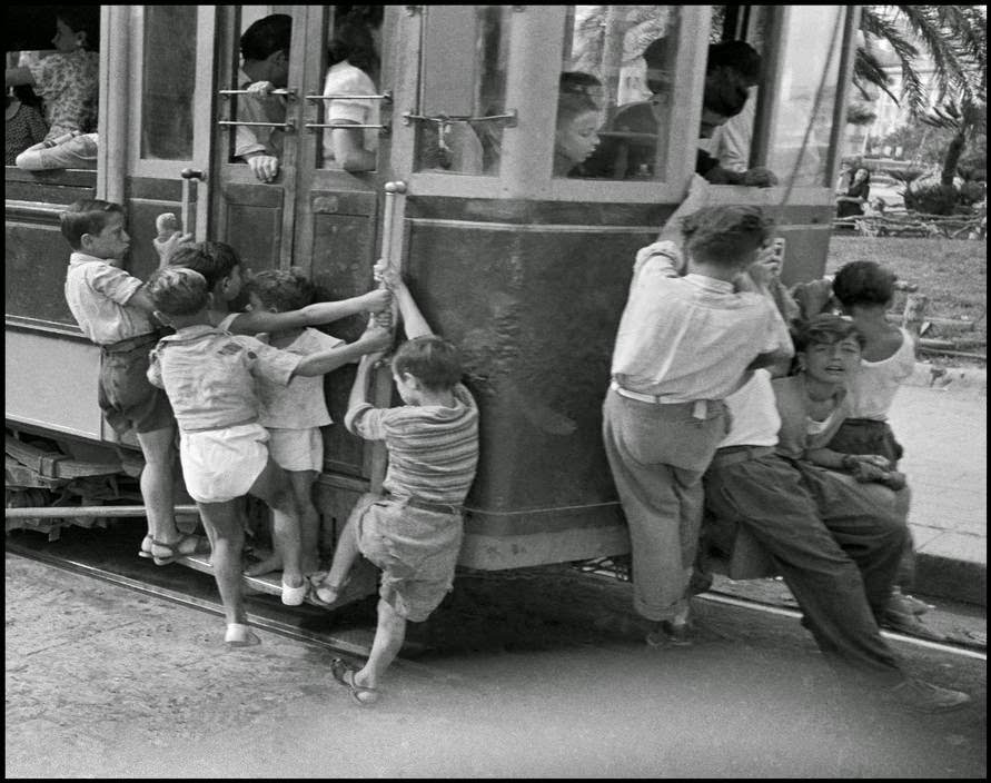 Young Neapolitans hanging on to the backs of streetcars in Naples, 1948