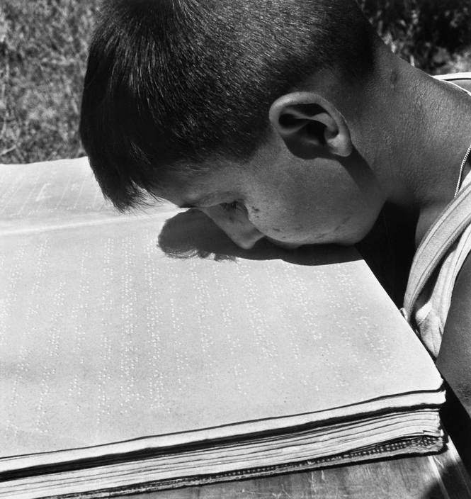 Blind boy who lost his arms during the war reading with his lips in Rome, 1948