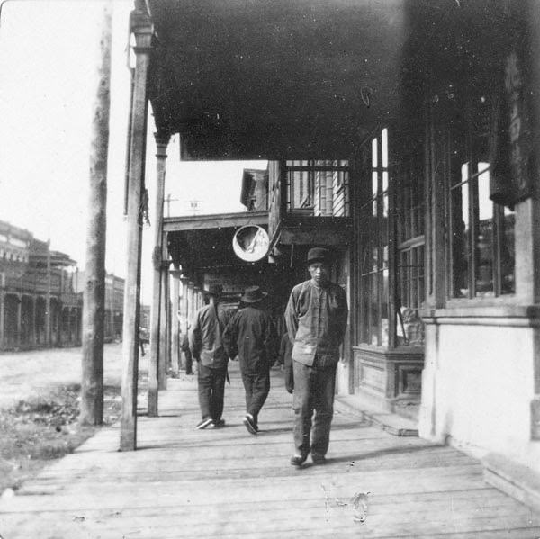 Man walking in front of stores, 1897.