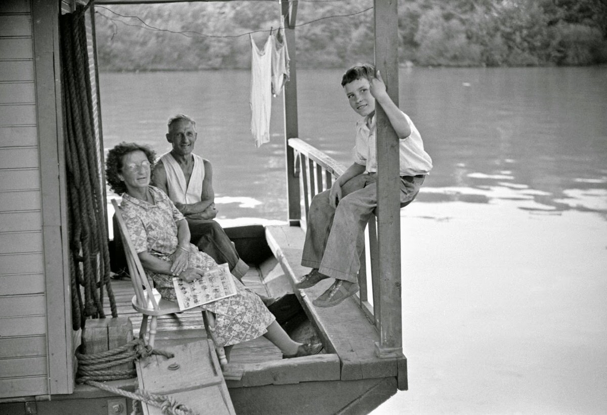 Family on front porch of houseboat on river