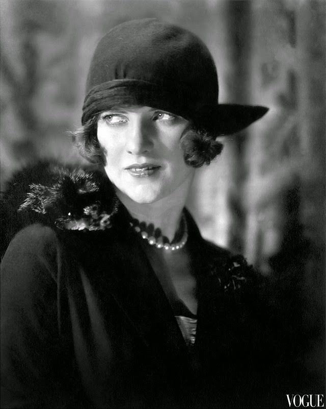 Actress-dancer Leonora Hughes in 1923 portrait, wearing dark cloche with brim jutting out on one side, pearls, and fur over shoulder.