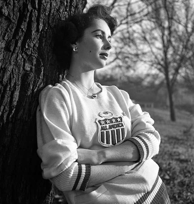 Liz Taylor gazes into the distance while wearing an "All America" sweatshirt, 1948.