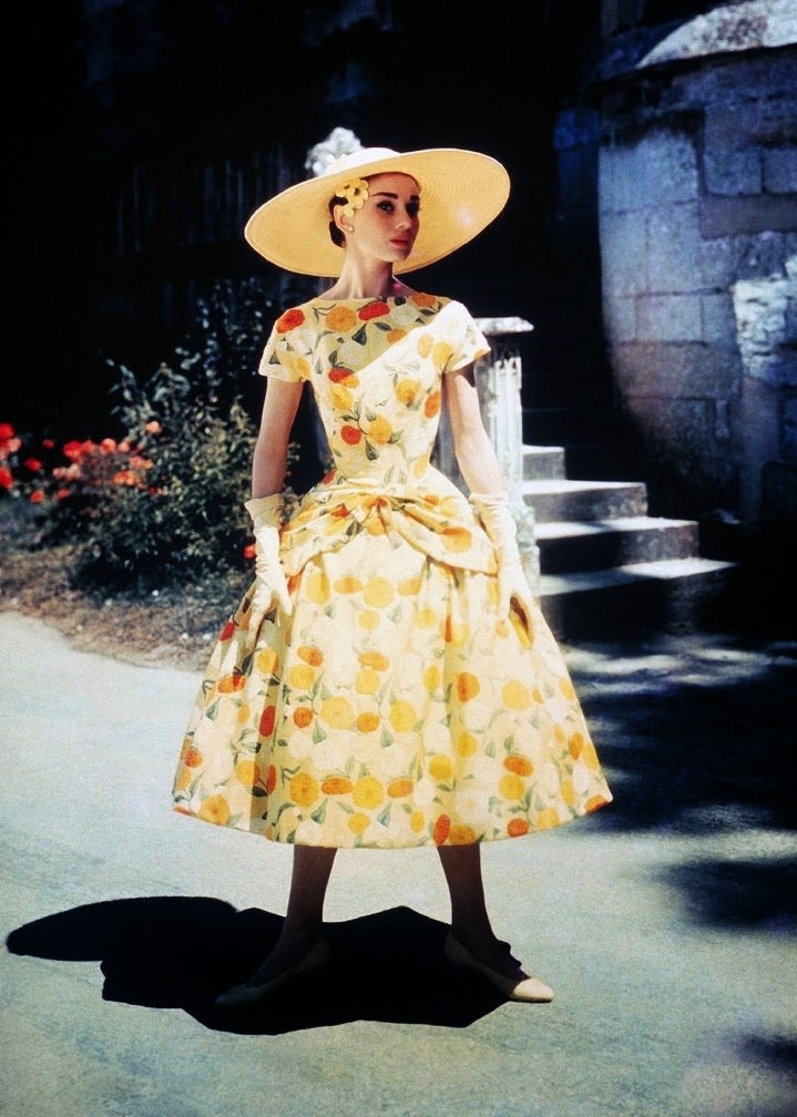 Audrey Hepburn on location for Funny Face in 1956 in a perfectly accessorised yellow print dress