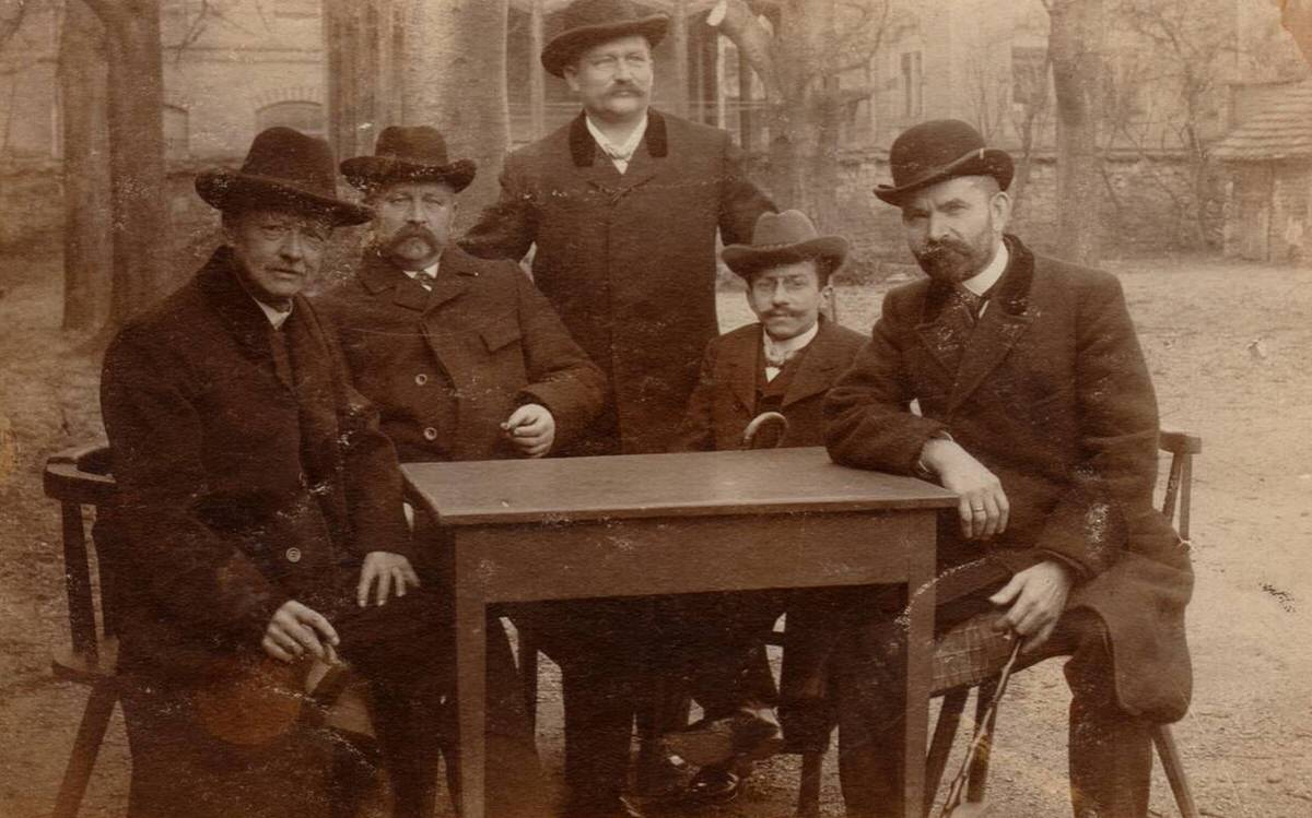 Men wearing bowlers sitting at a table in Germany, 1907