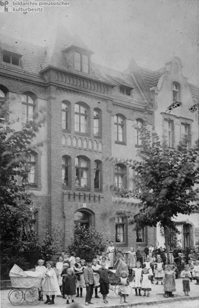 Here, a group of lower-middle-class children, who were probably part of an organized day-care group, can be seen in front of a row of houses in the Borsigwalde district of Berlin, c. 1910. Borsigwalde was a new community. It was developed in the late 1890s on the fallow Dalldorf Heaths for employees of the Borsig machine and locomotive factory.