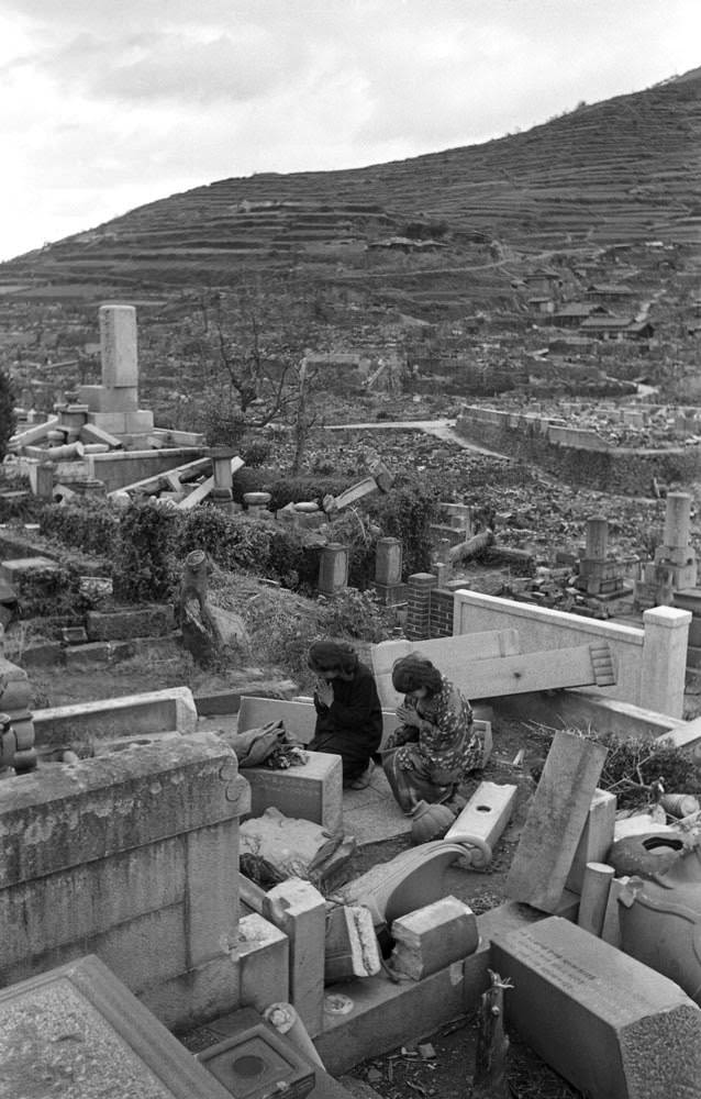 Two women pay respects at a ruined cemetery, Nagasaki, 1945.