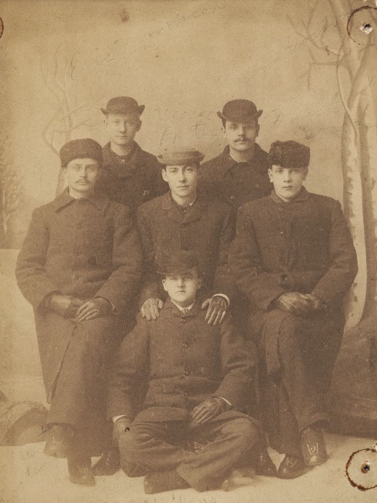 Studio portrait of six men in winter dress wearing hats, coats, and gloves, 1883