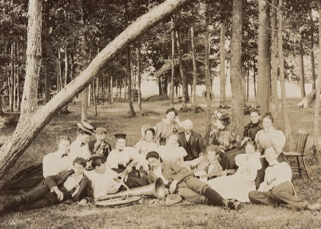 Group of seventeen men and women in a park setting, 1897