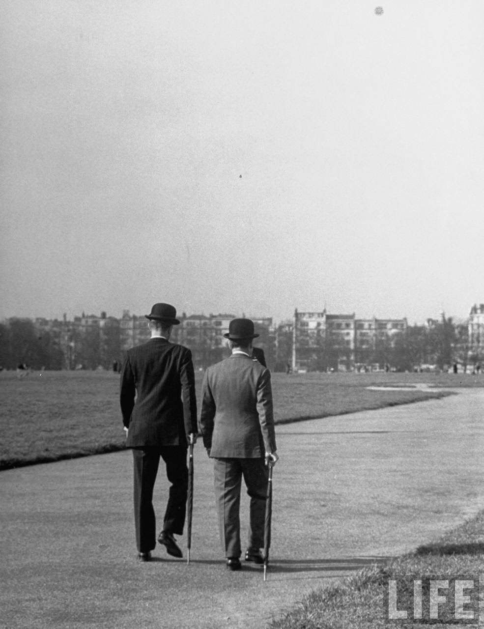 Two Englishmen, walking side by side along wide path keeping perfect step withone another.