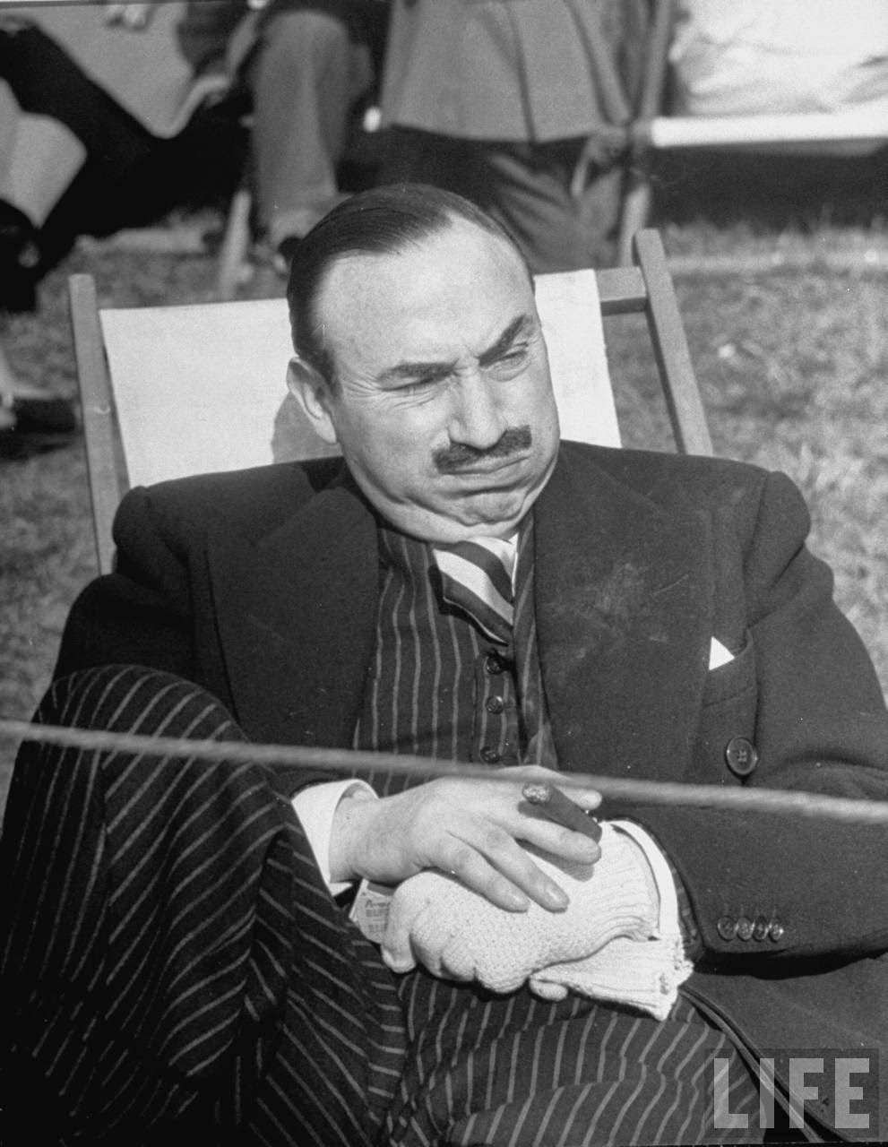 A man relaxing in the park while smoking a cigar.