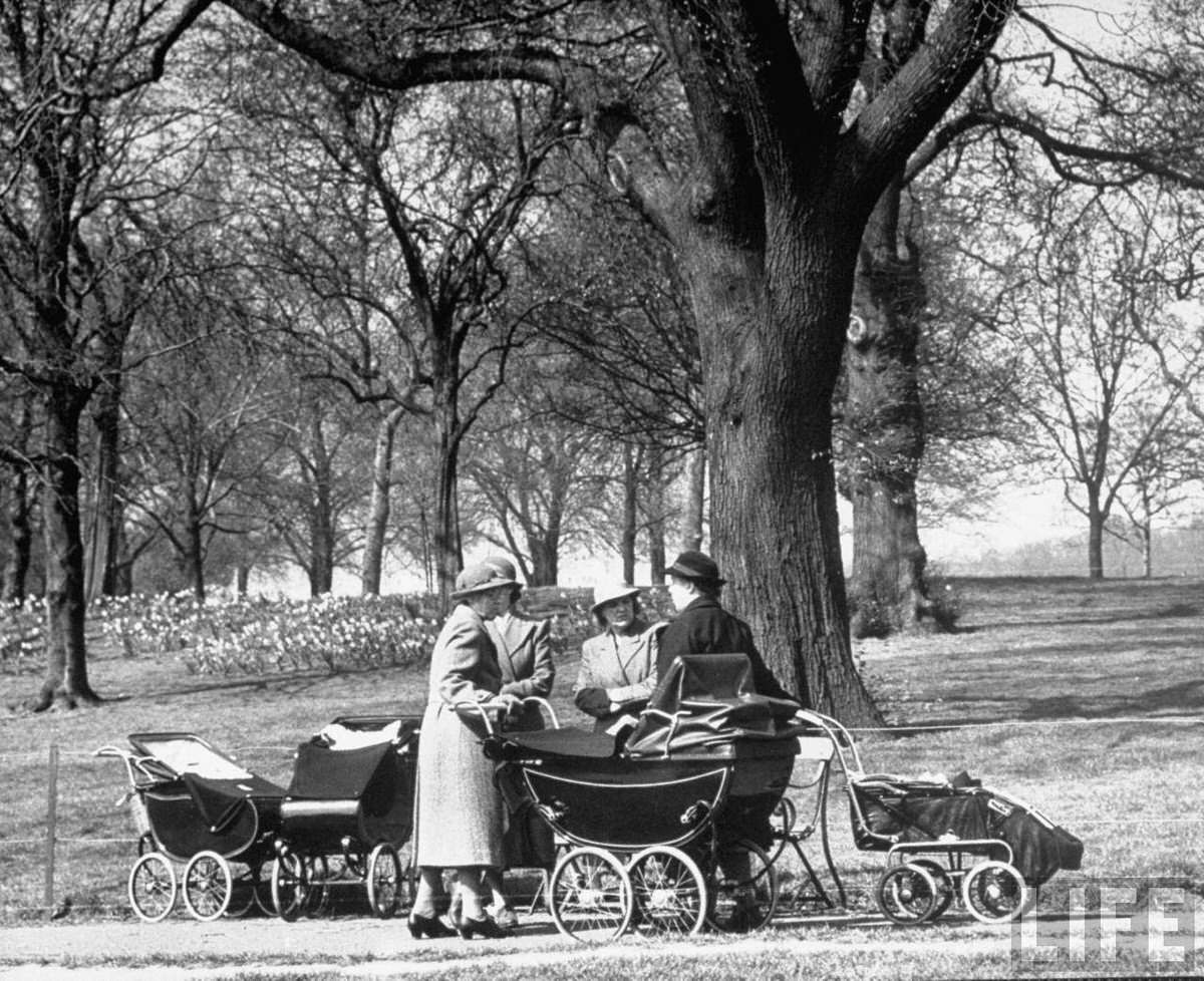 Woman walking their babies carriages and gossiping in the park.