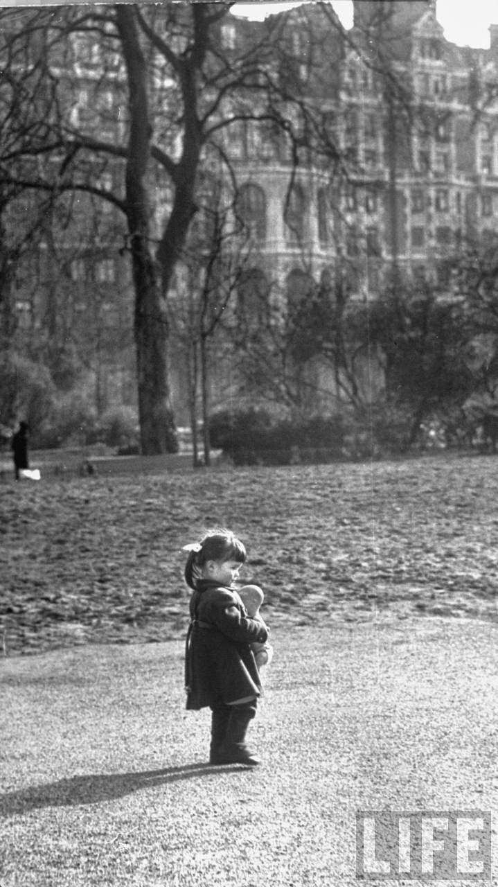 A little girl waiting to play in the park.