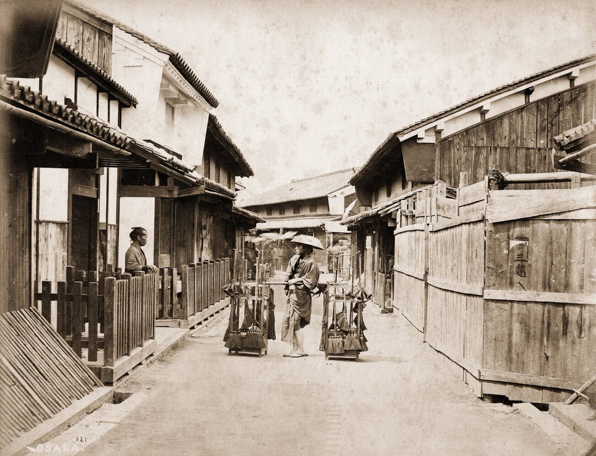 Broom vendor talking with a man in an Osaka backstreet.