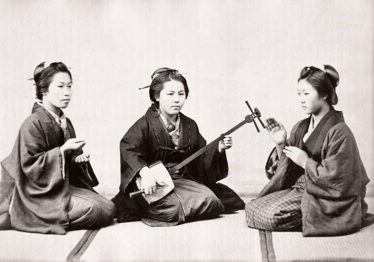 Girl playing a shamisen during a game of forfeits, 1871