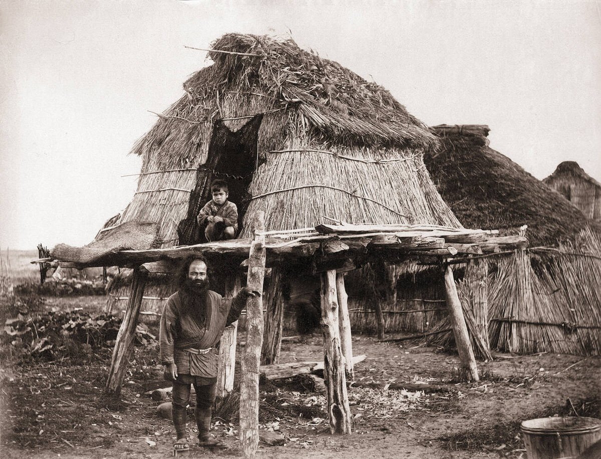 Ainu man and his son outside a storehouse in Hokkaido, 1870s