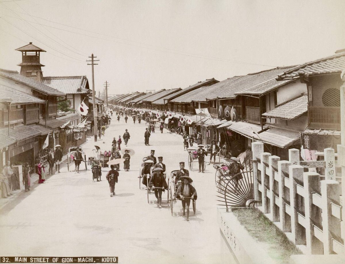 Main street of Gion-machi in Kyoto showing passengers in rickshaws, 1890