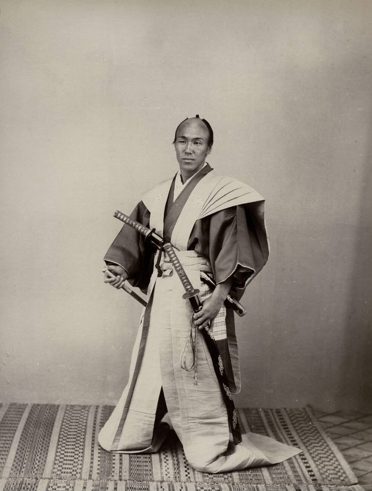 Samurai with two swords in a studio setting, 1880