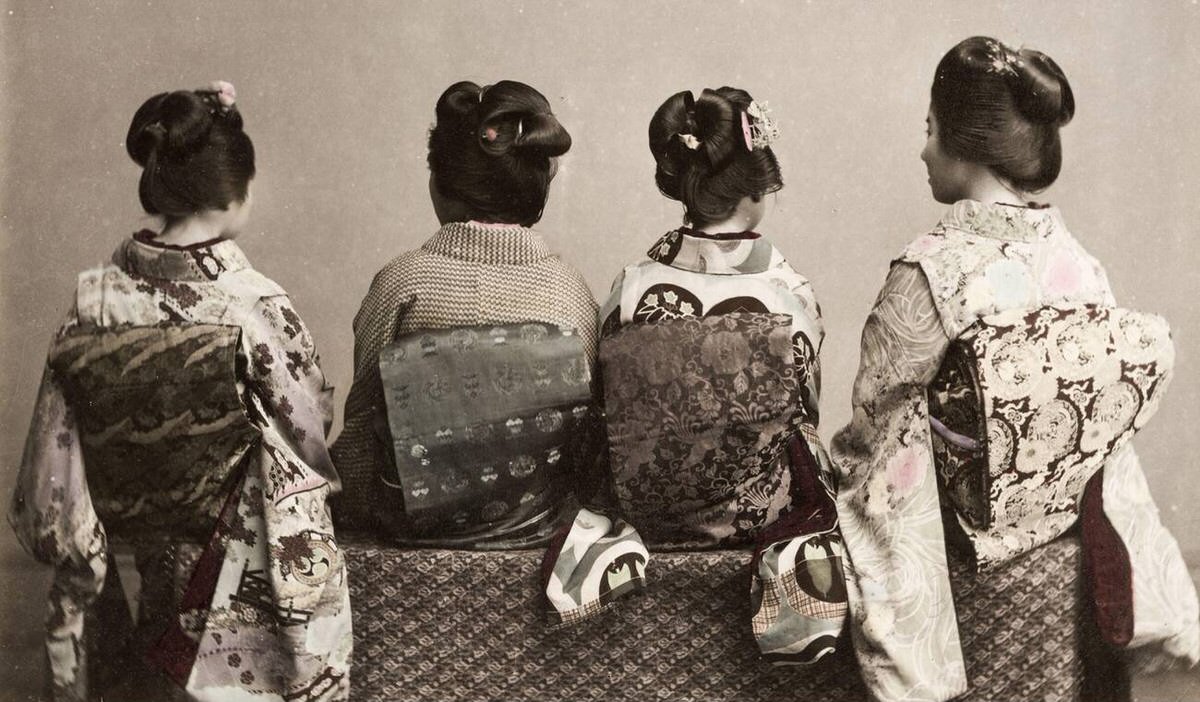 Back view of three girls showing ornate kimonos and obi sashes, 1890