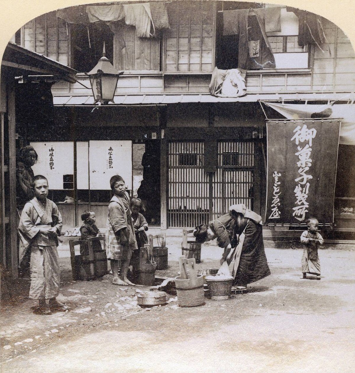 Woman washing clothes in wooden tubs on a street in Yokohama, 1890s