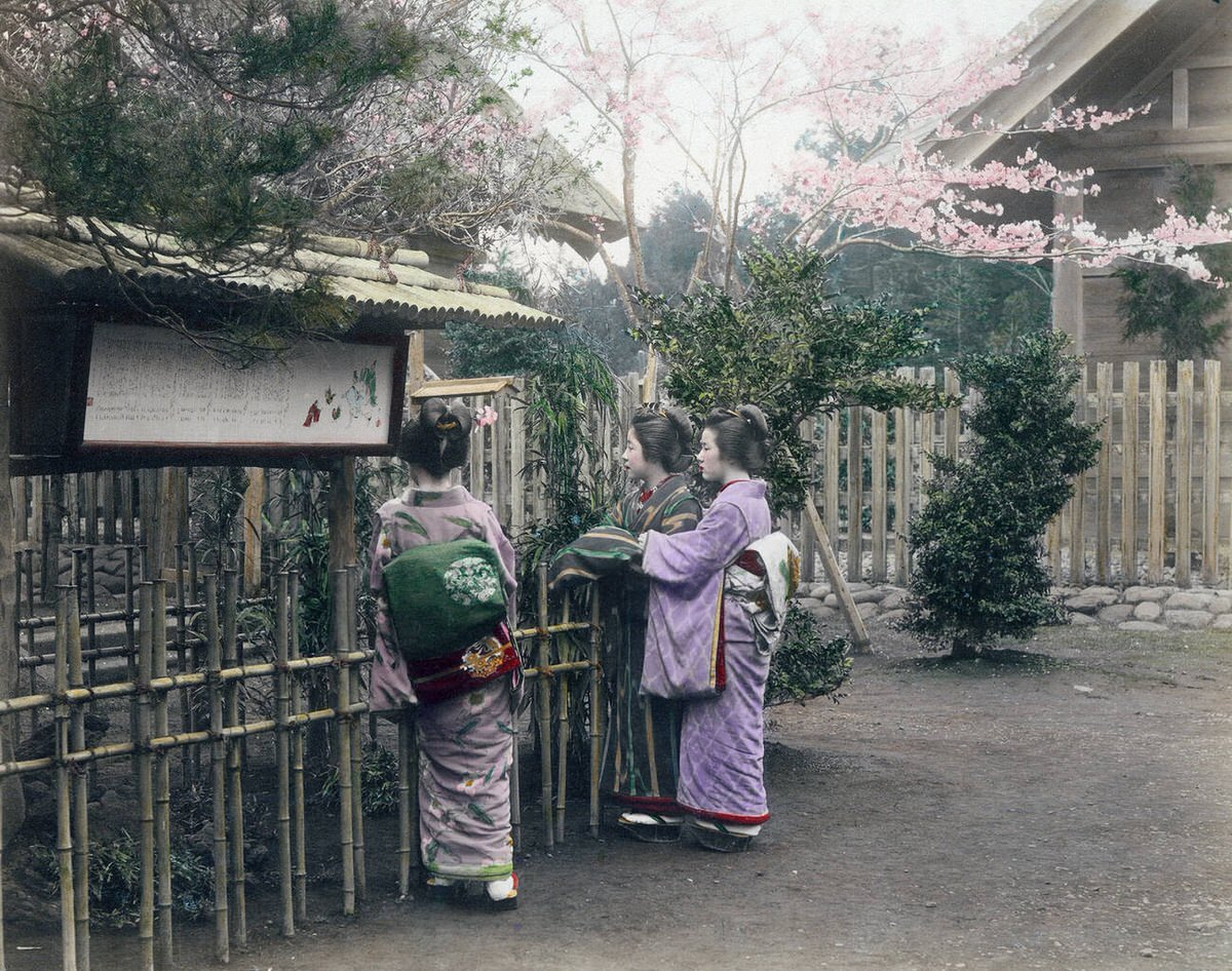Women in kimono reading a sign at a shrine or temple, 1890s